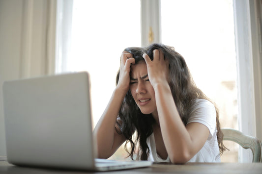 Junge Frau sitzt gestresst vor dem Laptop, die Hände in den Haaren, mit Sorgenfalten – sie weiß nicht, was sie für den Besuch ihrer Eltern in Bonn planen soll.